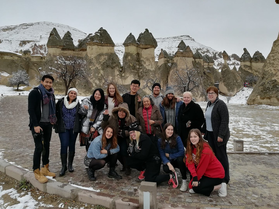 Group of tourists posing in front of unique rock formations.