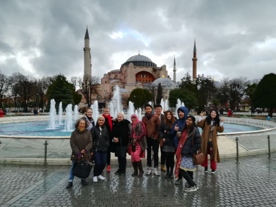 Group of tourists in front of the Hagia Sophia and fountains.