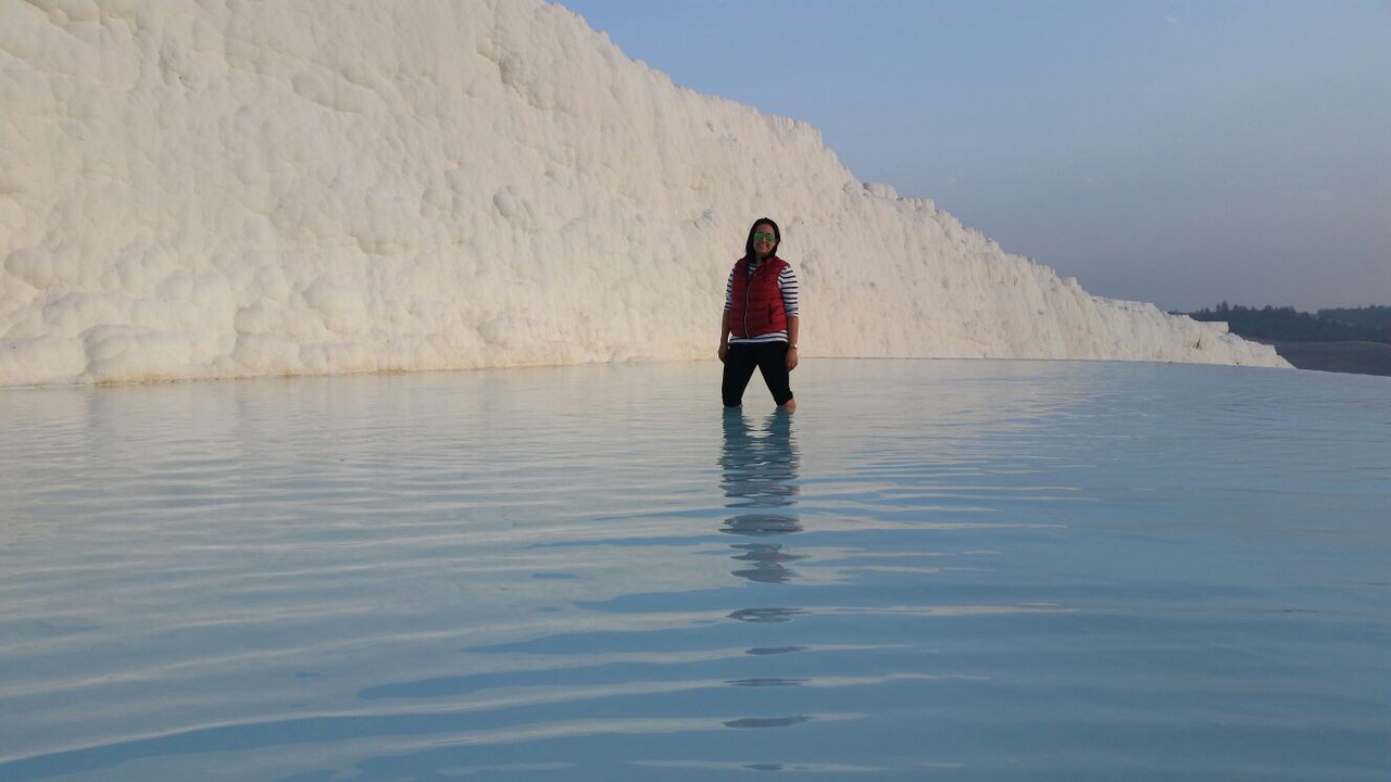 Person standing in water with white travertine terraces.
