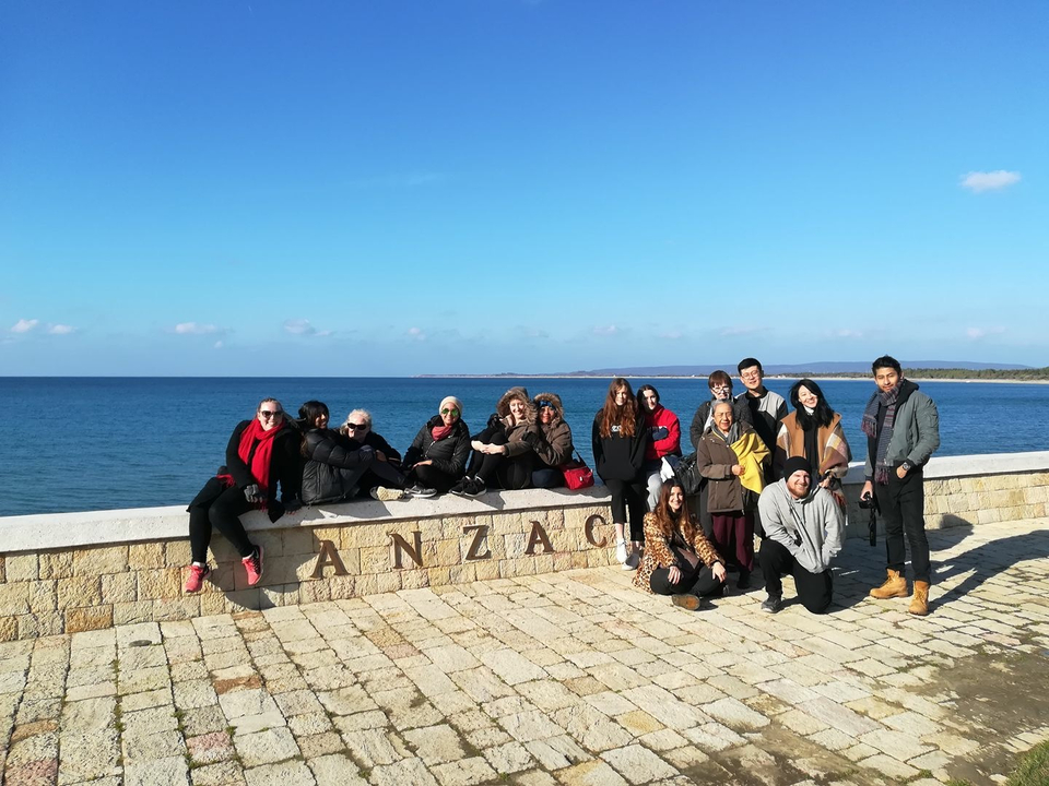 Group of people at ANZAC Cove by the sea.
