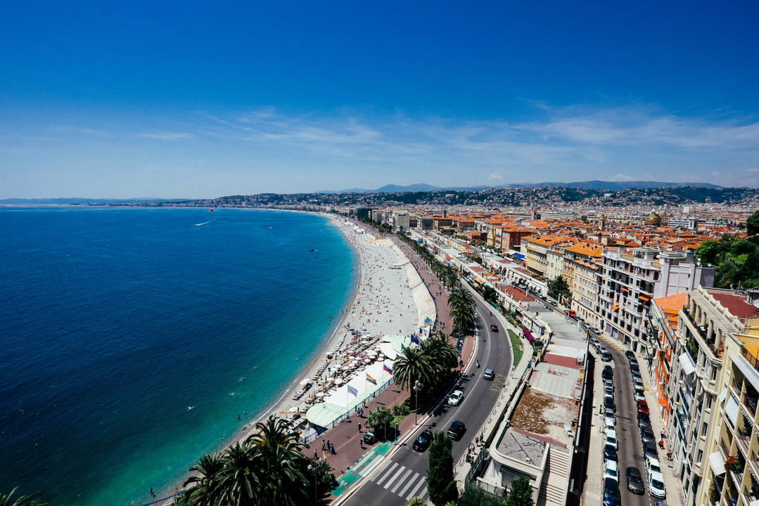 A long sandy beach with a promenade and buildings along the coastline.