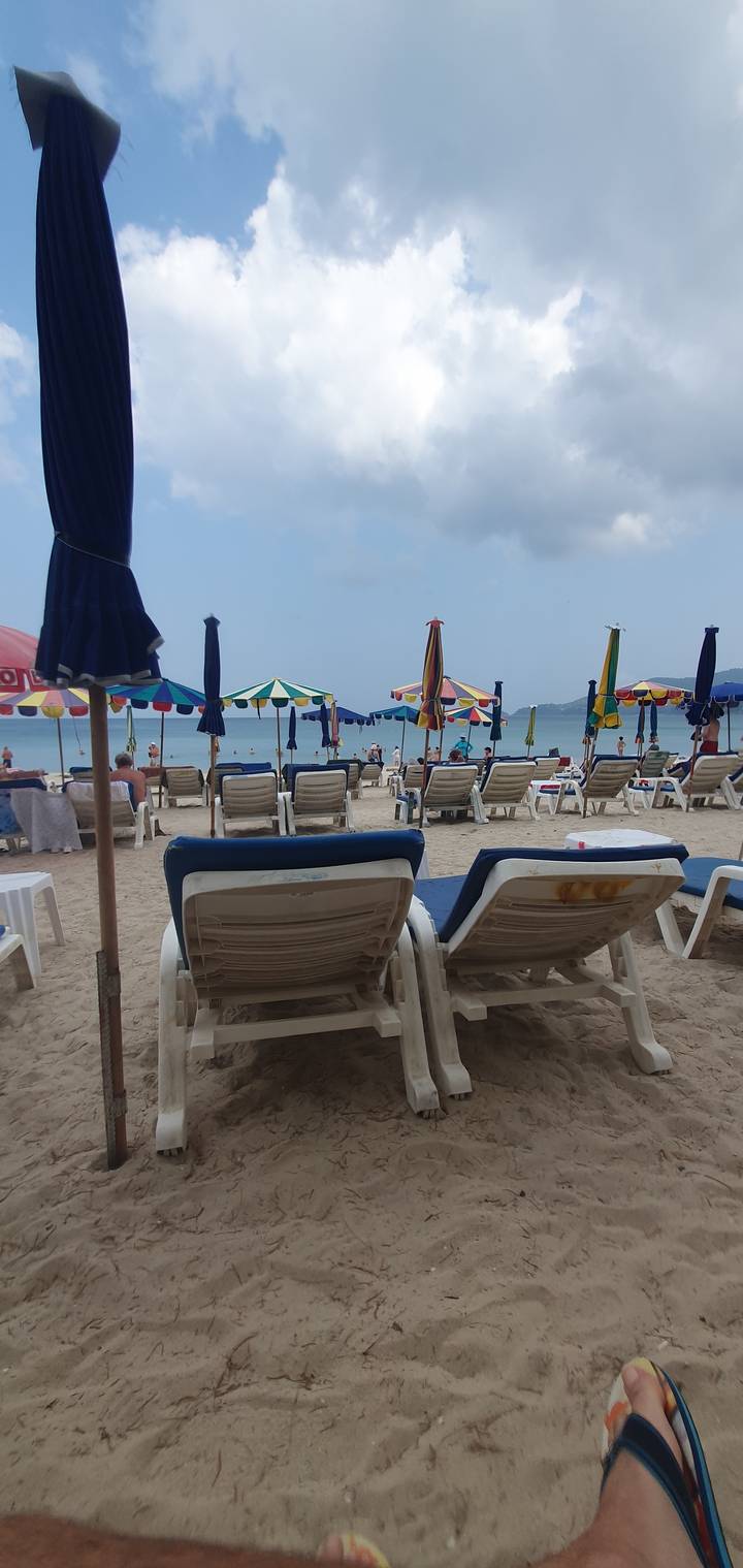 Beach scene with umbrellas and lounge chairs on sand.
