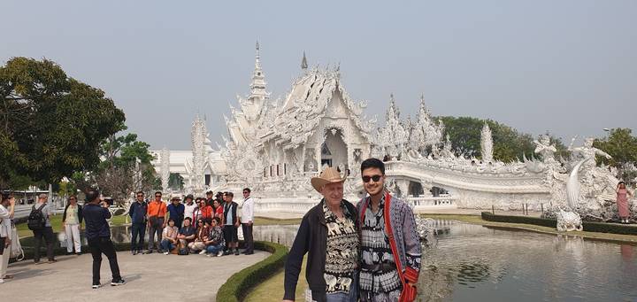 People standing in front of a large white artistic structure.