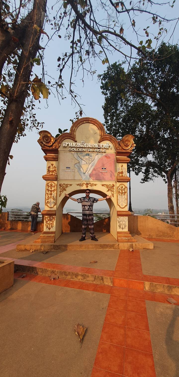 Person standing under a decorative sign with a scenic view.