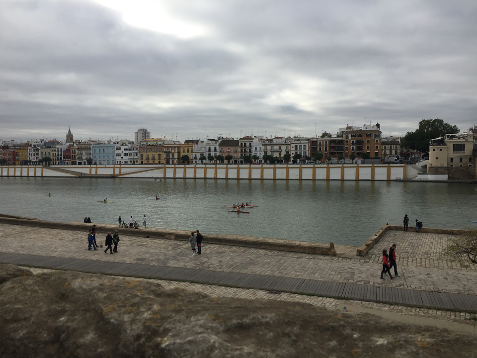 View of a city and river with people walking and kayaking.