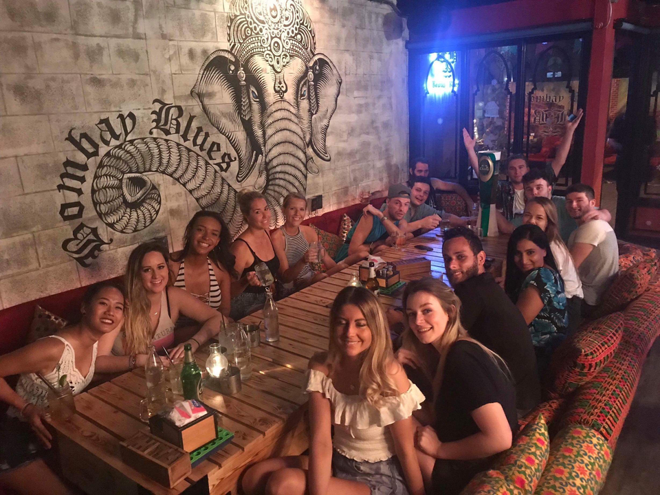 Group enjoying food and drinks in a lively restaurant with eclectic wall art.