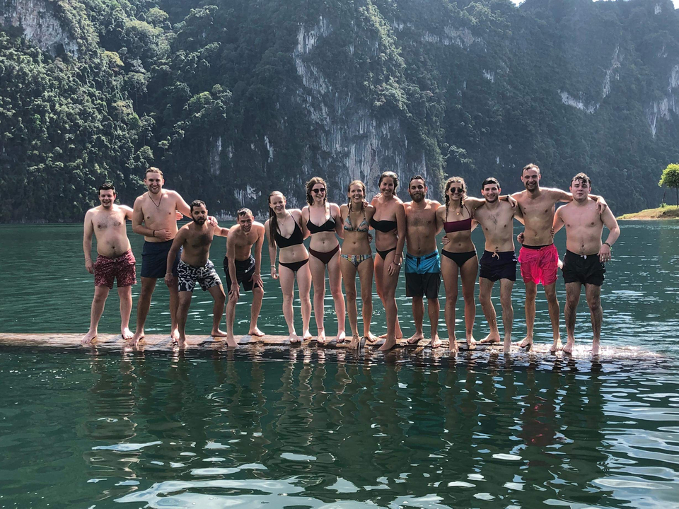 Group standing on a log in the water, smiling.