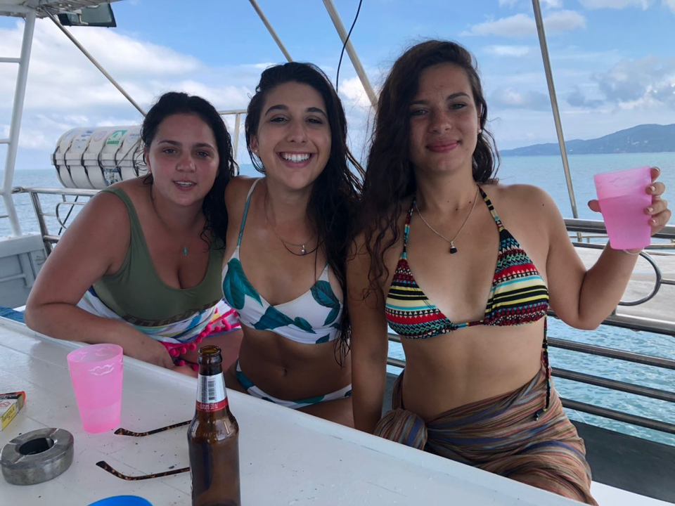 Three women enjoying a drink on a boat in the ocean.