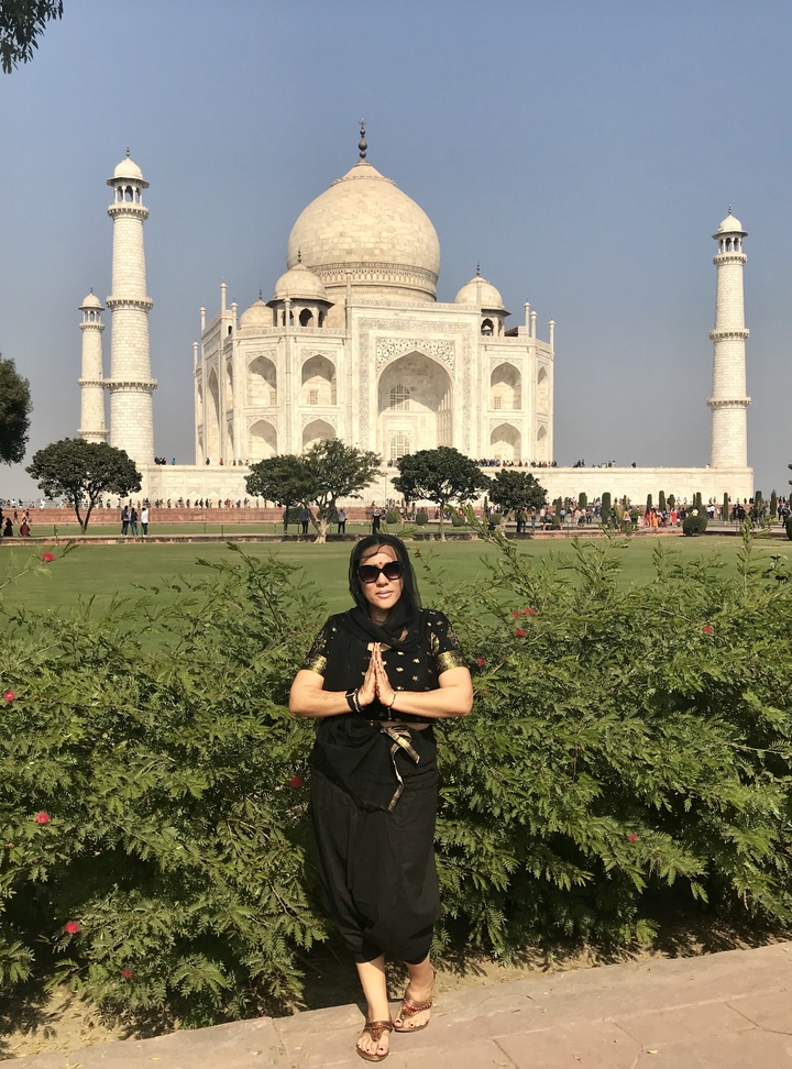 Une femme en tenue traditionnelle pose devant le Taj Mahal.
