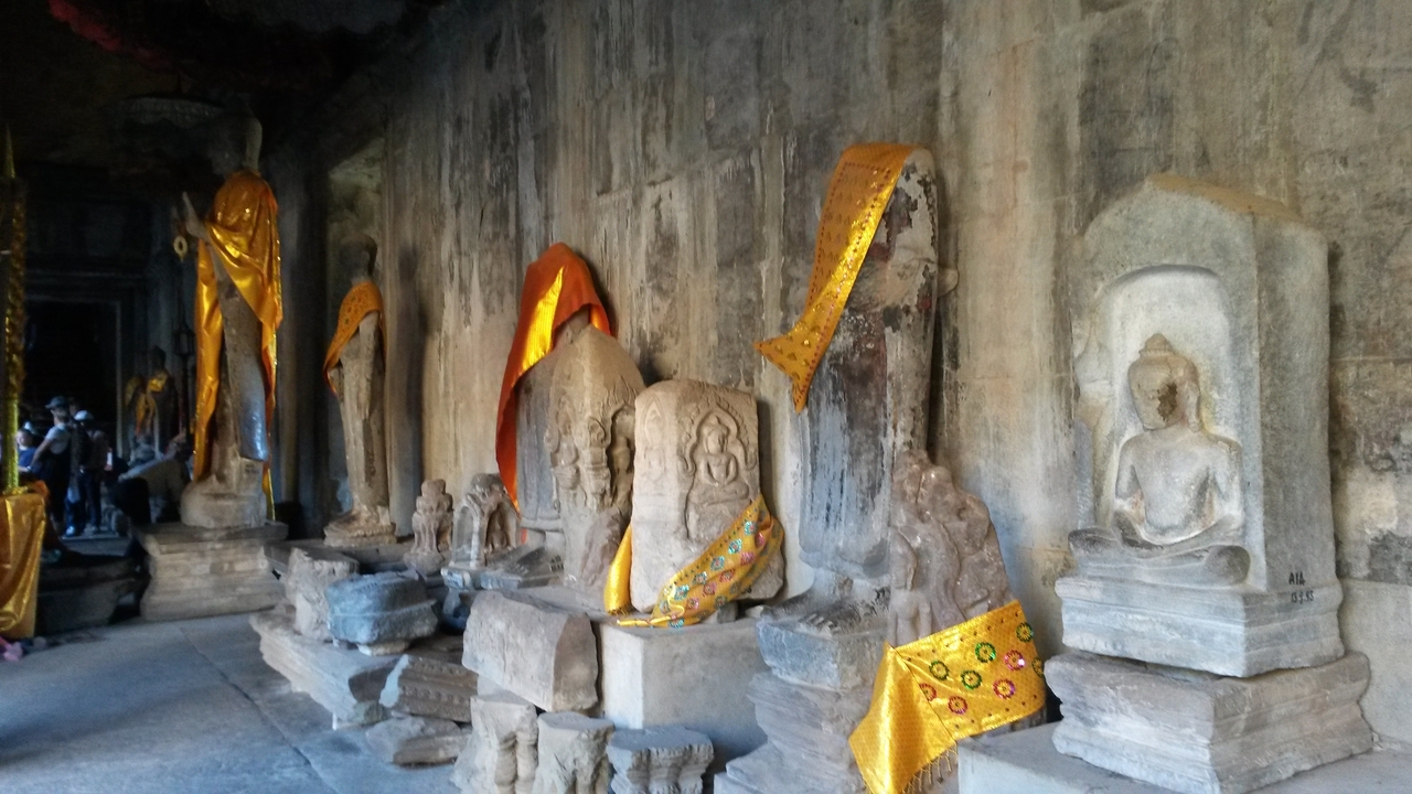 Stone statues in a temple with colorful fabric draped.