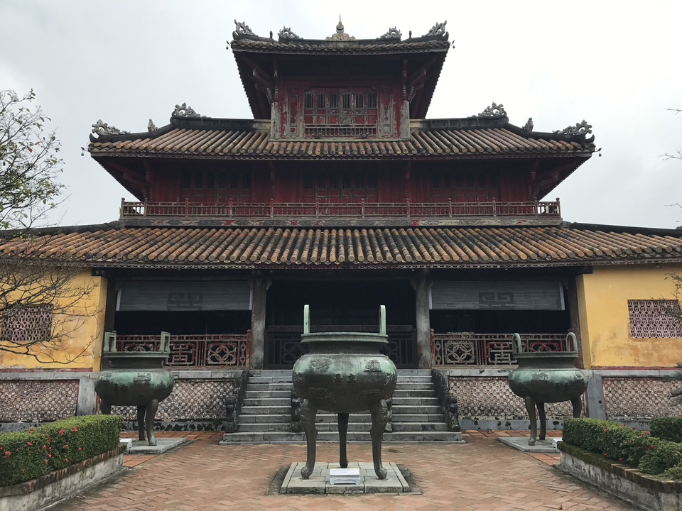 Traditional temple with a tiled roof and large pots in the foreground.