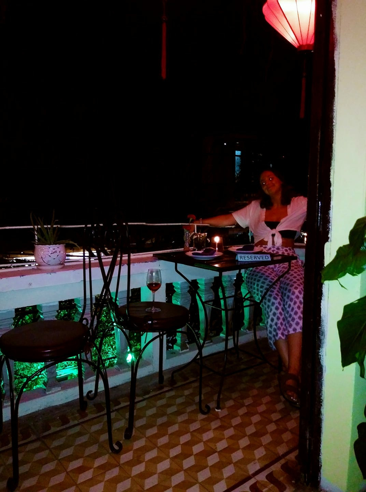 Person sitting in a dimly lit outdoor cafe setting.