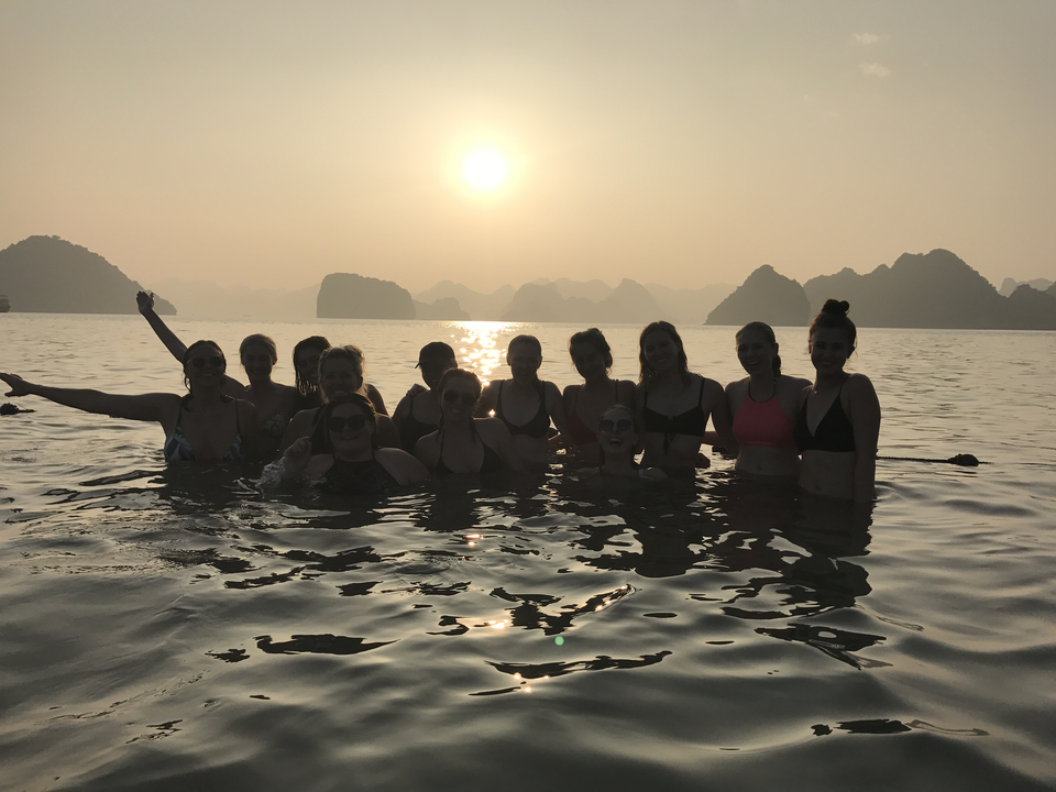Group of people enjoying a swim at sunset with scenic views.