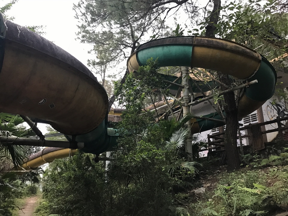 Abandoned water slide in a wooded area.