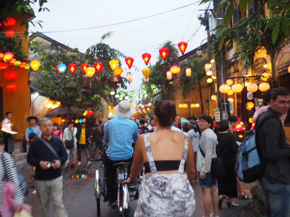 Busy street with colorful lanterns and people walking.
