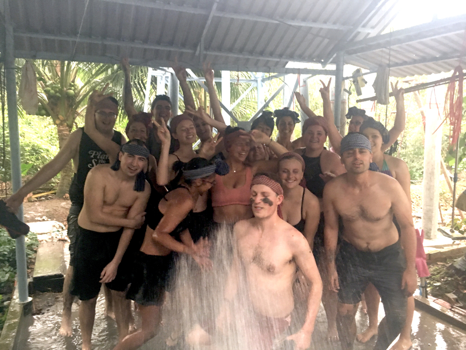 Group of people enjoying shower under a waterfall.