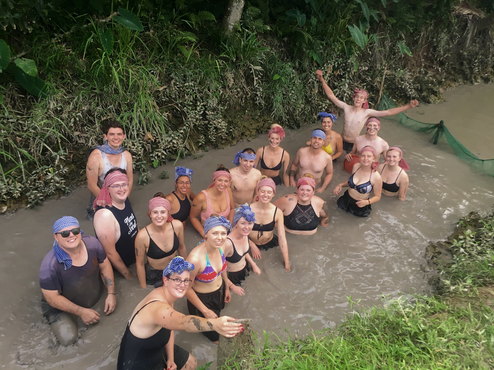 Group of people enjoying a water activity in a muddy area.