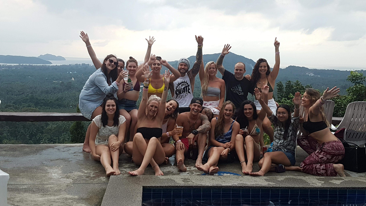 Group of people celebrating by a pool with a scenic view in the background.