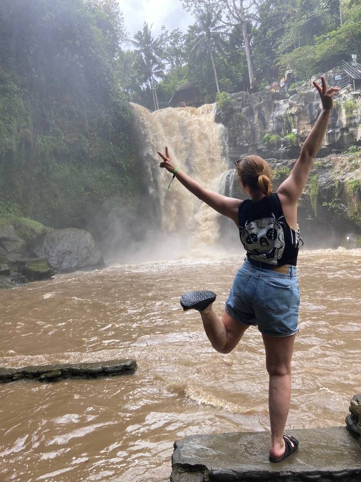 Young woman playfully posing near a waterfall.