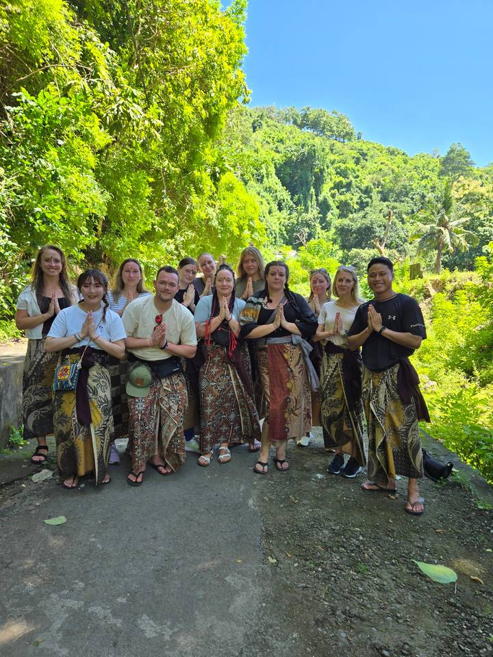 Group of people posing in traditional garments in a jungle setting.