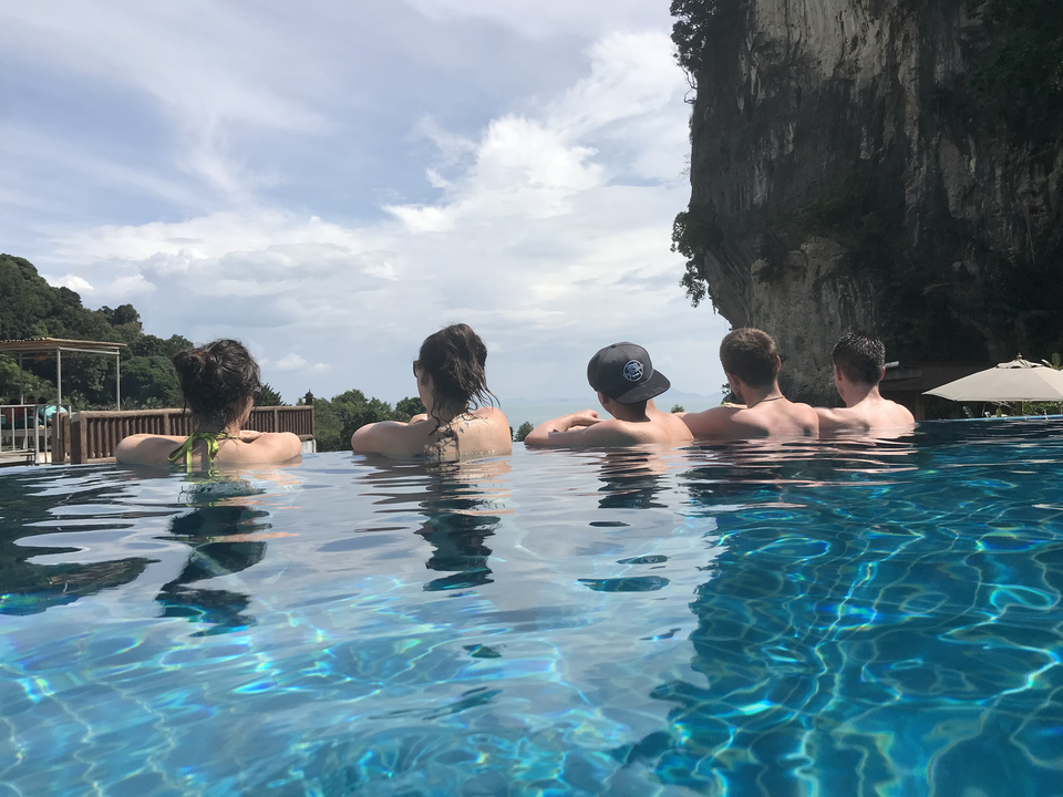 Group of people sitting in an infinity pool with views of the coast.