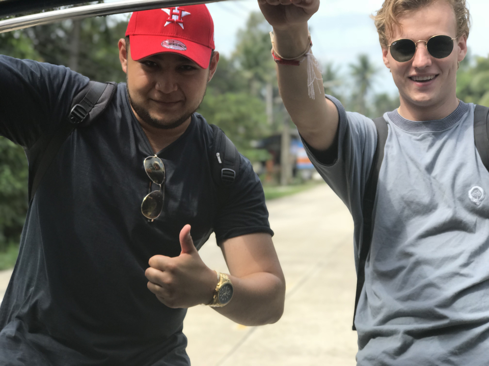 Two friends smiling and making gestures on a tropical street.