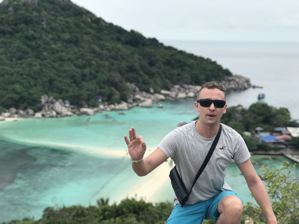 Person enjoying a scenic viewpoint overlooking turquoise waters and islands.
