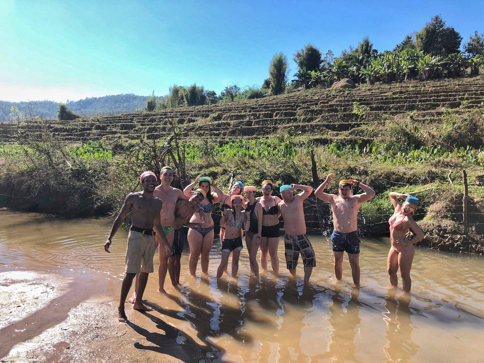 Group posing in a rural area with terraced fields in the background.
