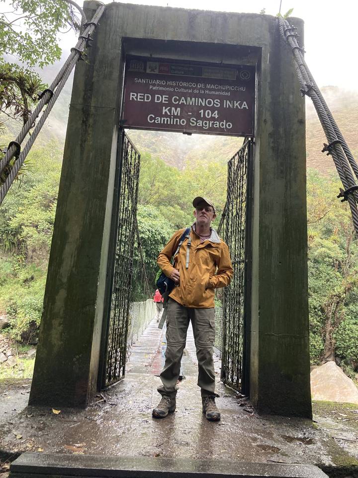 Person standing at an archway entrance with a sign.