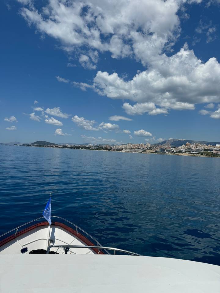 Coastal view with a boat approaching a city.