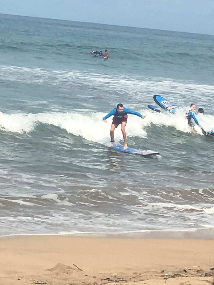 Person surfing on a wave with another surfer in the background.