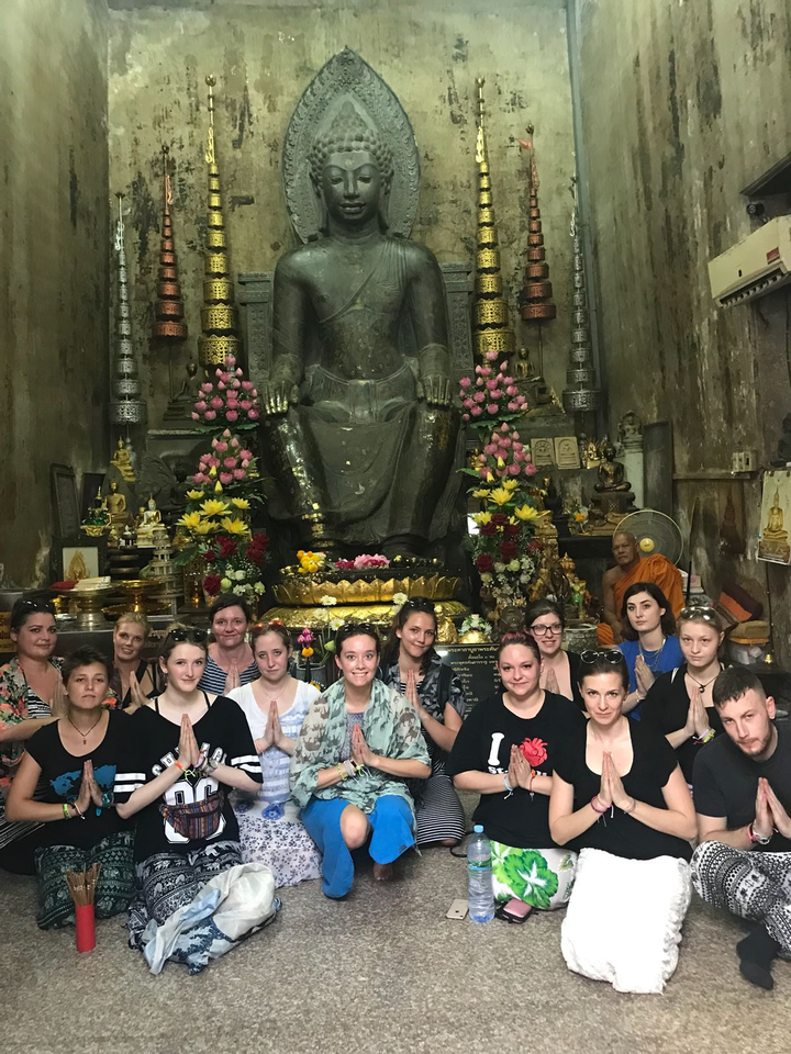 Group posing inside a temple with statues and offerings.