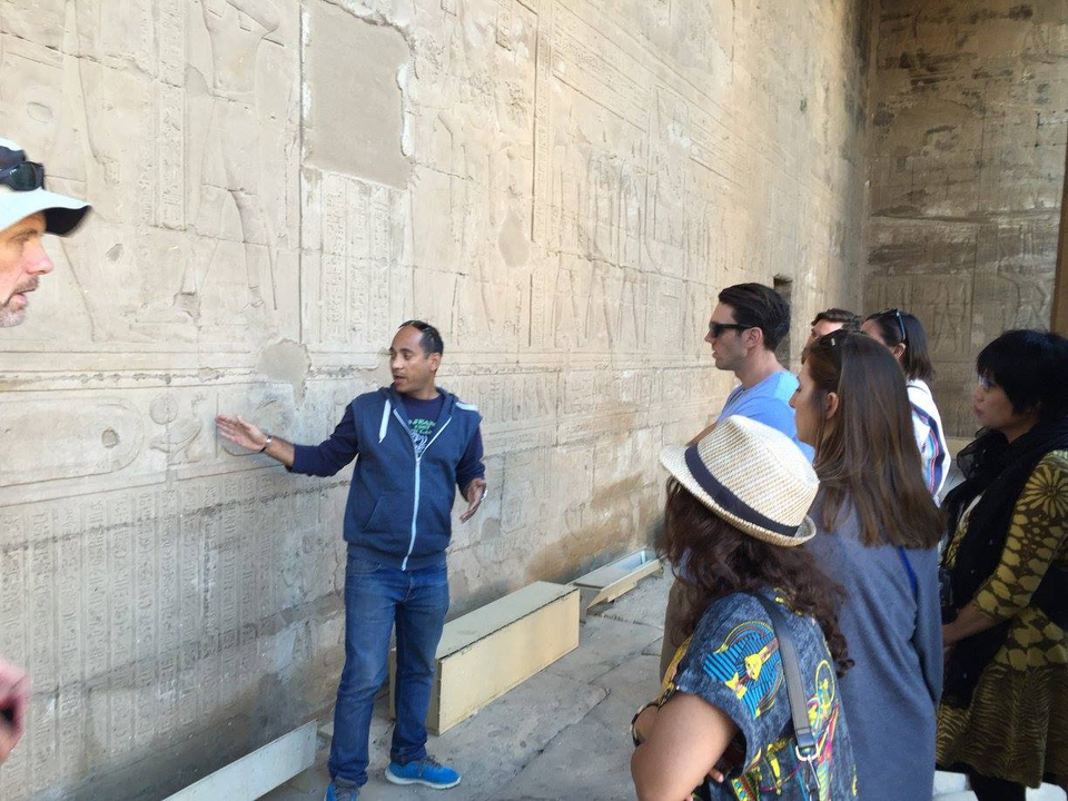 A tour guide explaining ancient carvings to a group.
