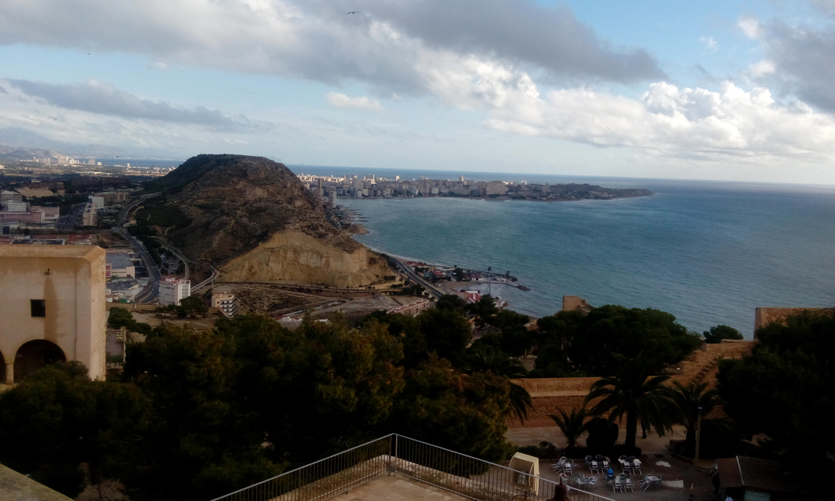 Coastal cityscape with mountains and sea view.