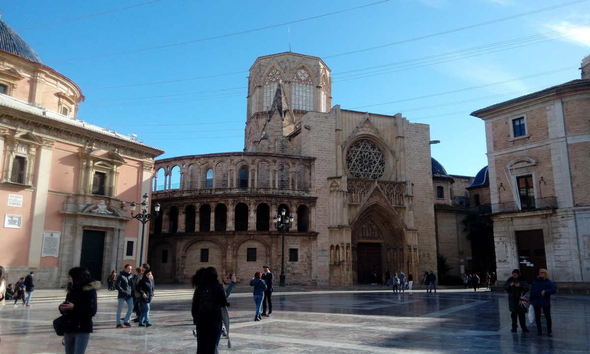 Historical cathedral in a city square with people walking.