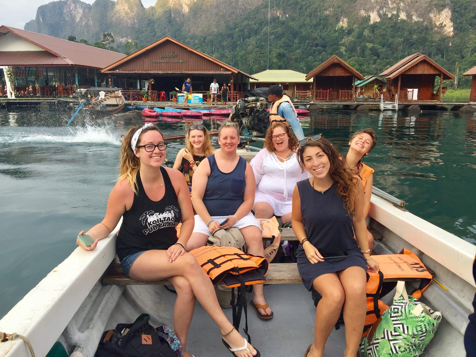 Groupe de personnes assises dans un bateau sur un lac avec des maisons flottantes.
