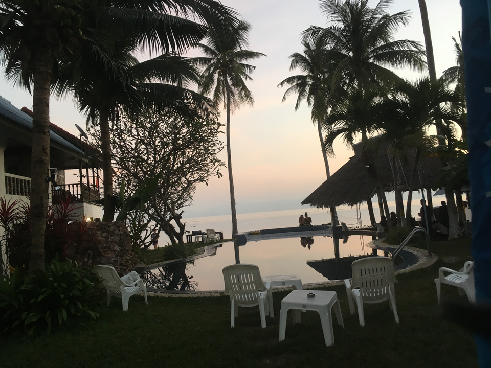 Zone de villégiature au bord de la plage au coucher du soleil avec des gens qui se détendent.