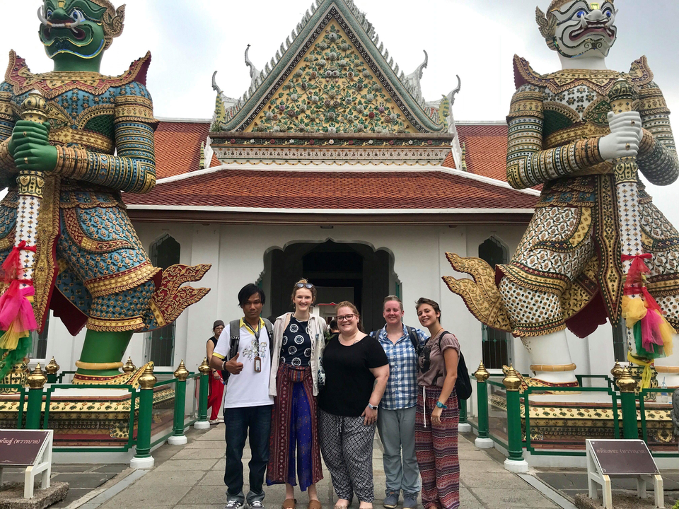 Groupe de personnes posant devant un temple avec des statues.