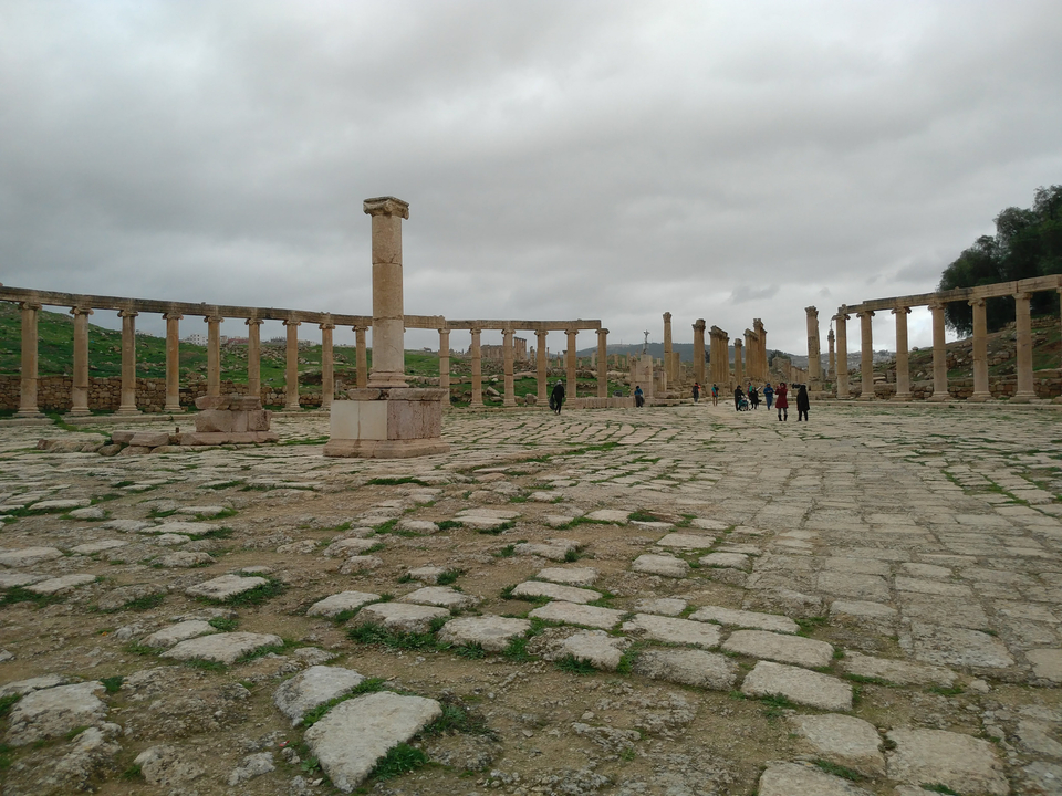 Ruins of columns and stones with people walking.