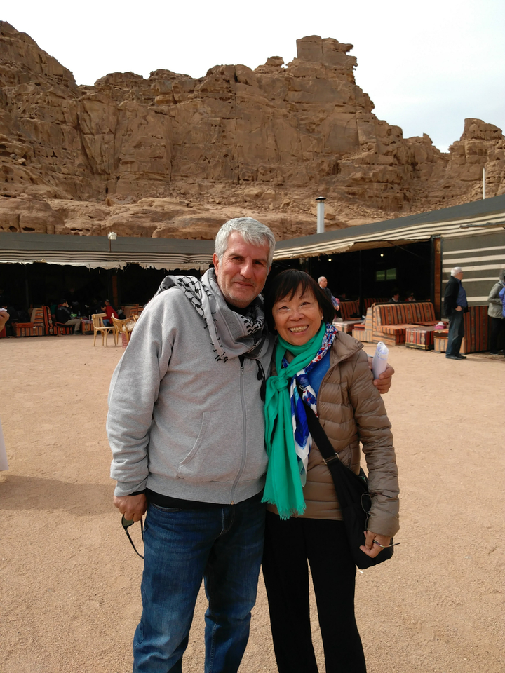 Two people smiling in front of desert tents.