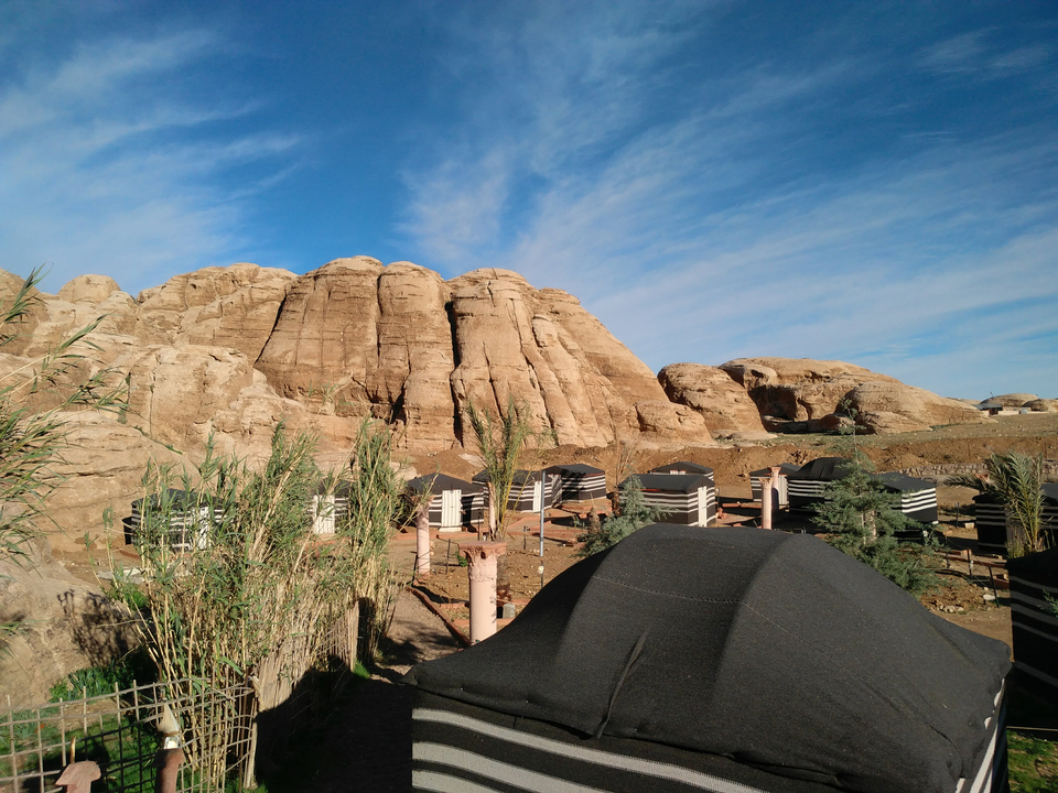 Rocky desert landscape with tents and vegetation.