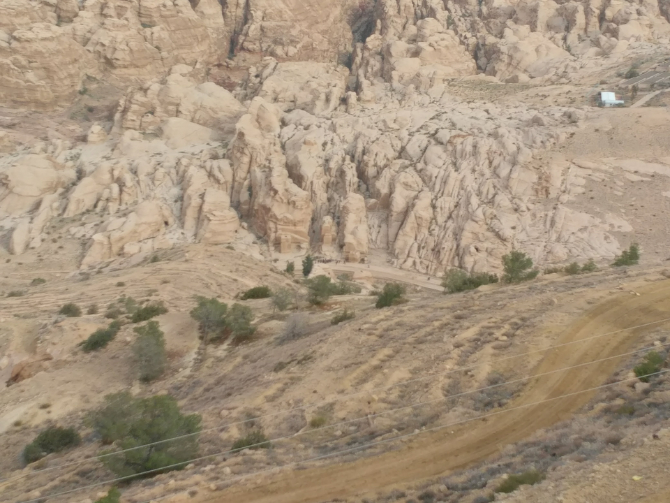 Rocky landscape with scattered trees and dirt paths.