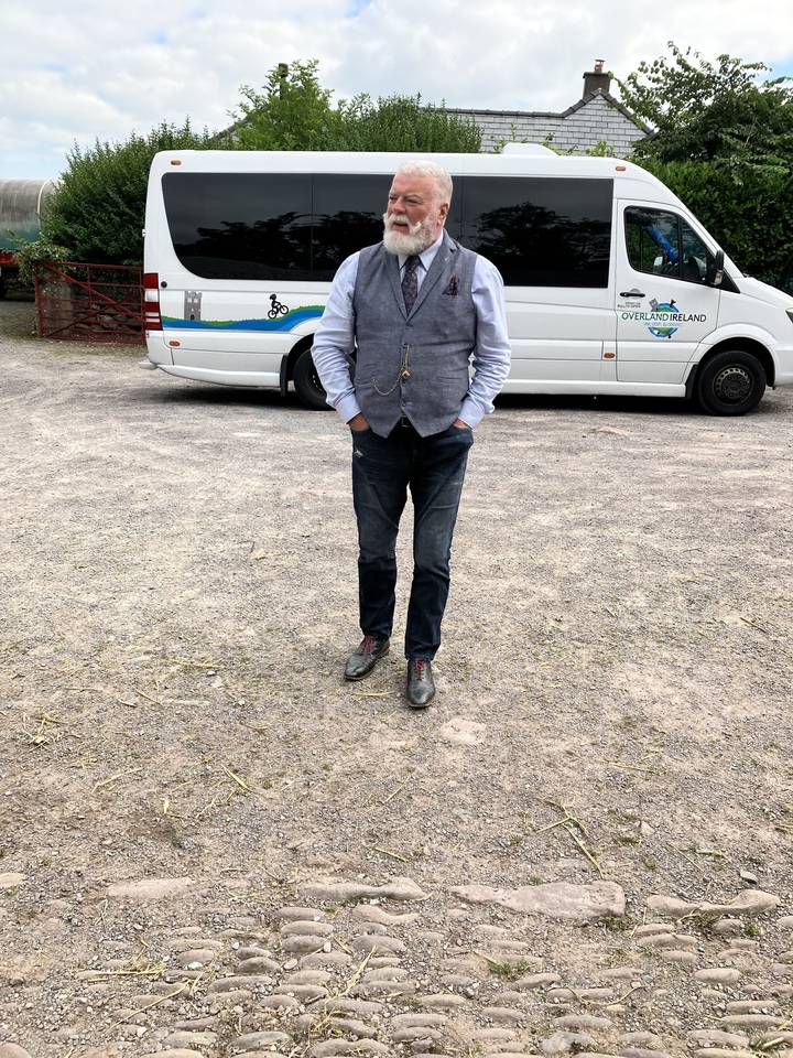 An older man standing in front of a tour van.