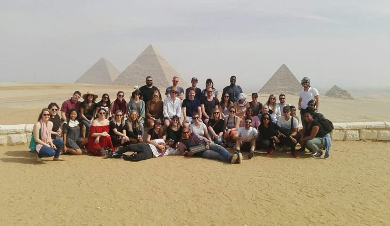 Group of people posing with pyramids in the background.