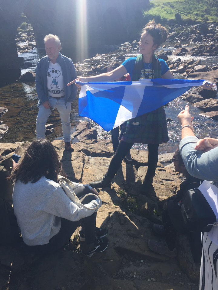 Group of people with a Scottish flag by a river.
