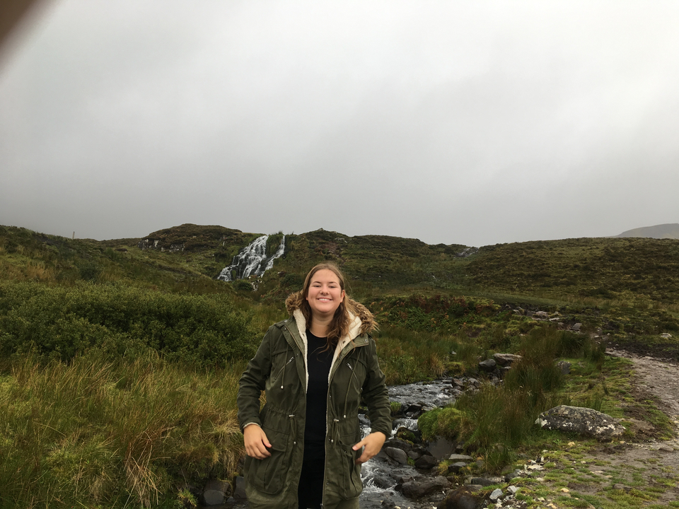 Young woman posed in front of a waterfall.