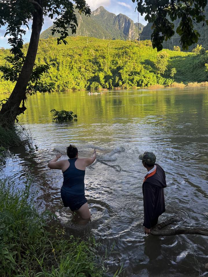 People playing in a river surrounded by lush greenery.