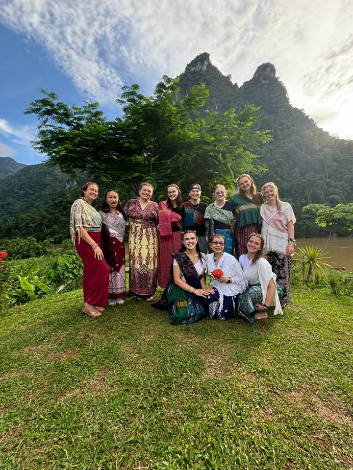 Group of women in traditional attire posing outdoors.