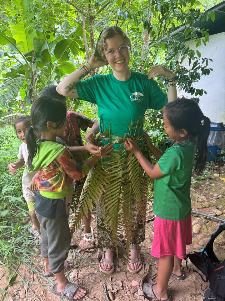 Woman surrounded by children, preparing traditional crafts.