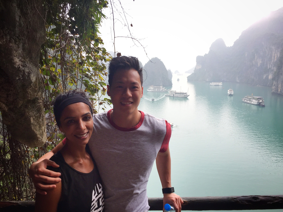 Two people smiling with Ha Long Bay scenery in the background.